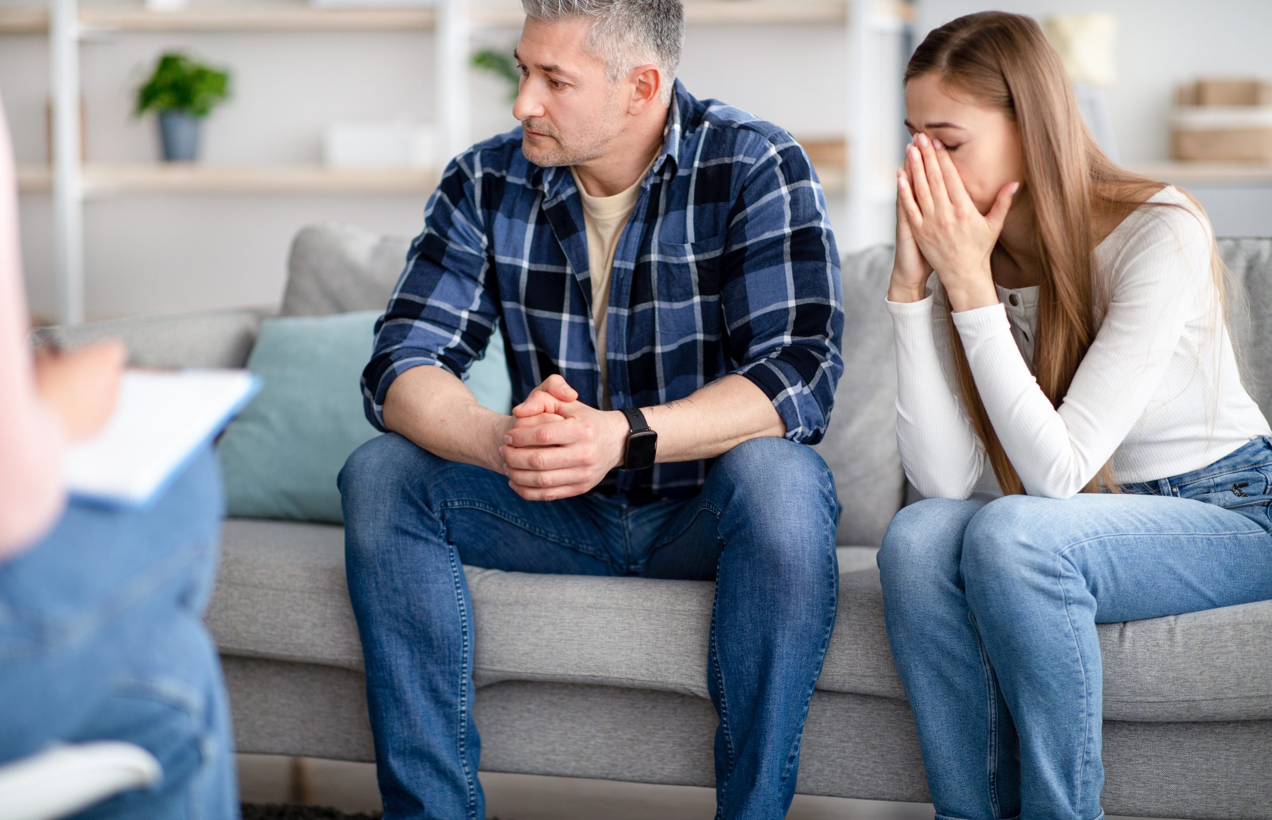 Man en vrouw die naast elkaar op de bank zitten bij een relatietherapeut en het vertrouwen in hun relatie kwijt zijn